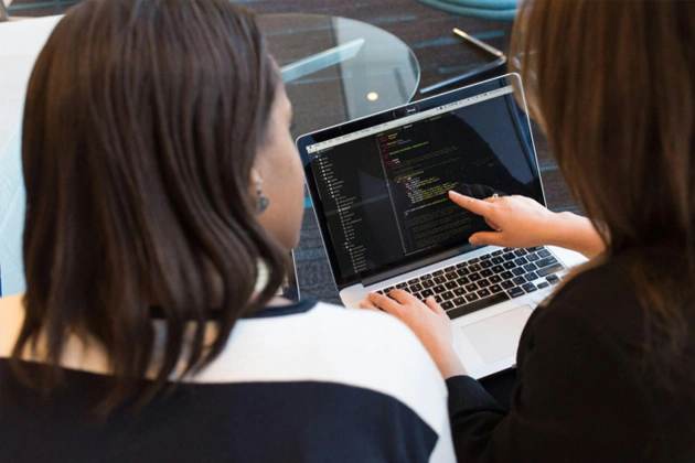 woman using macbook pro with person in white top woman using macbook pro with person in white top